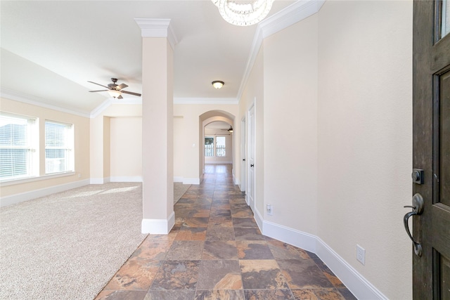 hallway featuring a chandelier, dark carpet, a wealth of natural light, and crown molding