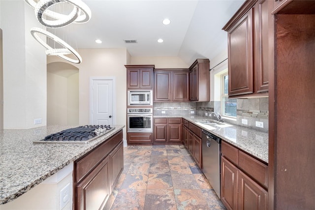 kitchen with pendant lighting, an inviting chandelier, sink, appliances with stainless steel finishes, and light stone counters