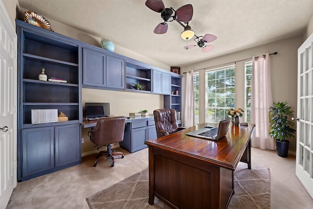 office space with light carpet, french doors, ceiling fan, and built in desk