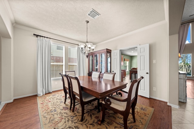 dining room featuring hardwood / wood-style flooring, plenty of natural light, ornamental molding, and a notable chandelier