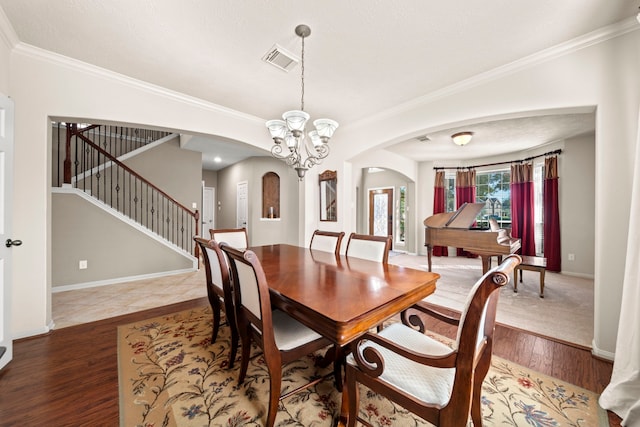 dining space with a chandelier, hardwood / wood-style floors, and crown molding