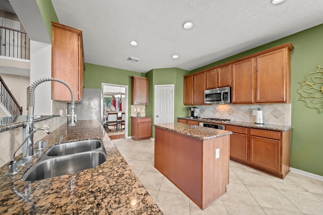 kitchen with a textured ceiling, stone countertops, light tile patterned flooring, and sink