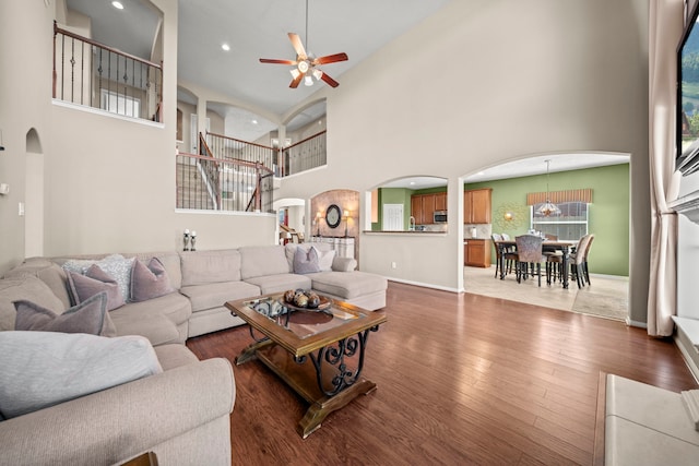 living room with ceiling fan, wood-type flooring, and a high ceiling