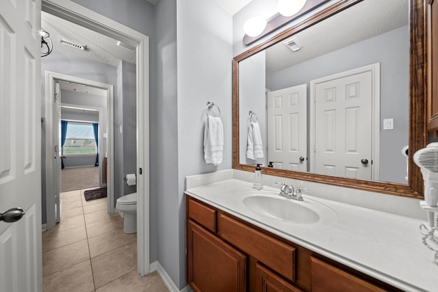 bathroom with tile patterned flooring, vanity, a textured ceiling, and toilet