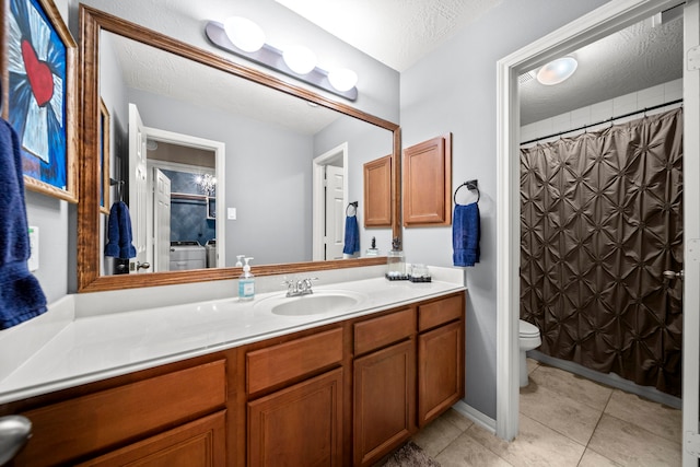 bathroom featuring vanity, tile patterned floors, washer and dryer, toilet, and a textured ceiling