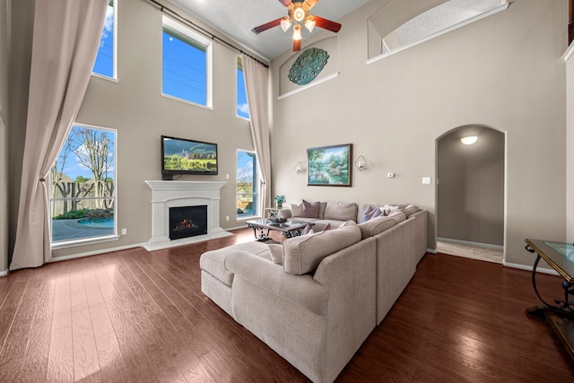 living room with a high ceiling, dark hardwood / wood-style flooring, and ceiling fan