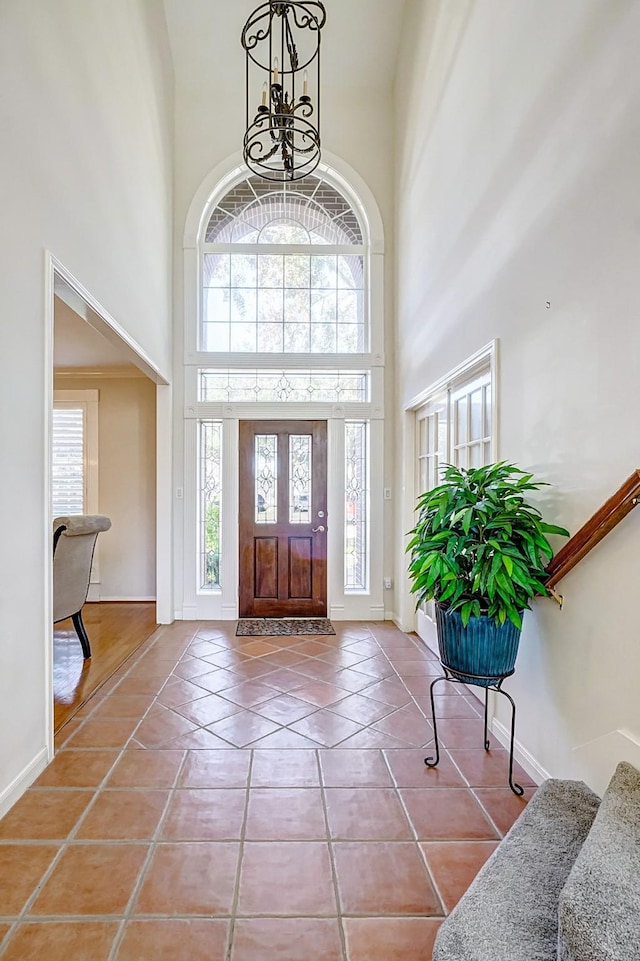 tiled entrance foyer featuring a high ceiling and an inviting chandelier