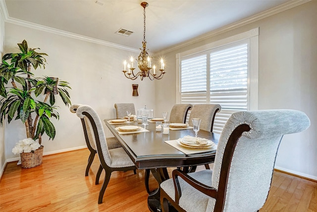 dining room featuring ornamental molding, hardwood / wood-style flooring, and a notable chandelier