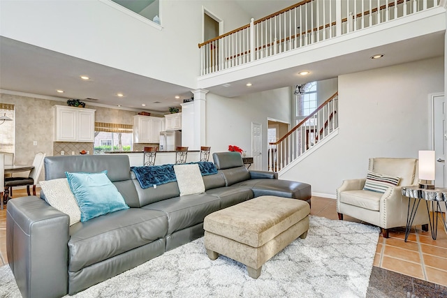 living room with decorative columns, crown molding, tile patterned flooring, and a towering ceiling