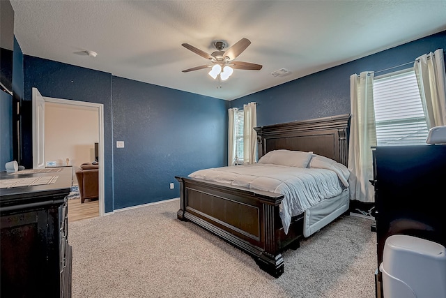 carpeted bedroom with a textured ceiling, ceiling fan, and multiple windows