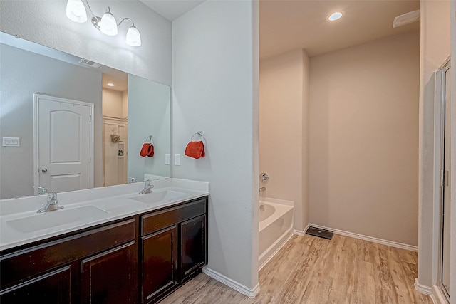 bathroom with hardwood / wood-style flooring, vanity, and shower with separate bathtub