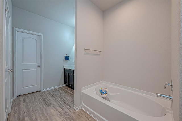 bathroom featuring a washtub, hardwood / wood-style floors, and vanity