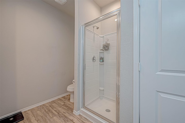 bathroom featuring wood-type flooring, toilet, and a shower with door