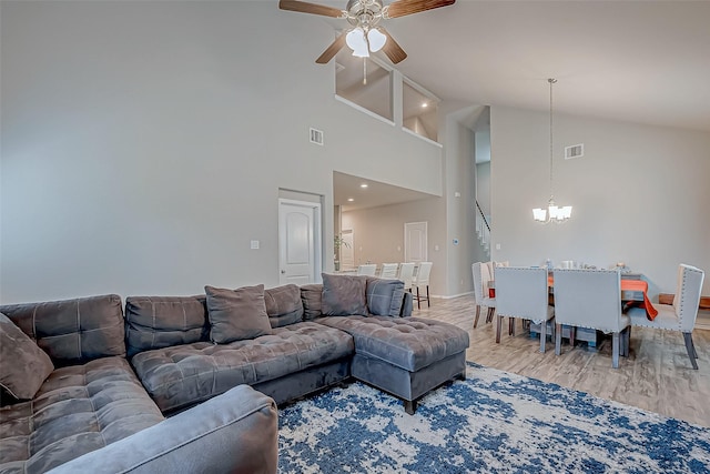 living room featuring high vaulted ceiling, wood-type flooring, and ceiling fan with notable chandelier