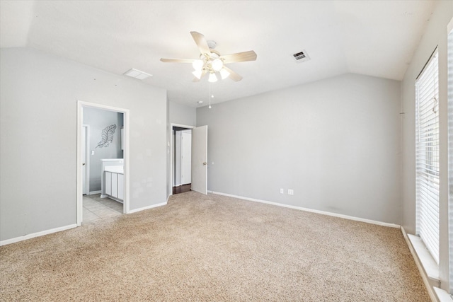 unfurnished bedroom featuring ensuite bath, ceiling fan, light carpet, and vaulted ceiling