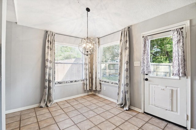 unfurnished dining area with a chandelier, light tile patterned floors, a textured ceiling, and a healthy amount of sunlight