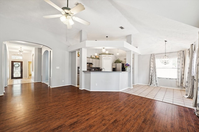 unfurnished living room featuring vaulted ceiling, wood-type flooring, and ceiling fan with notable chandelier