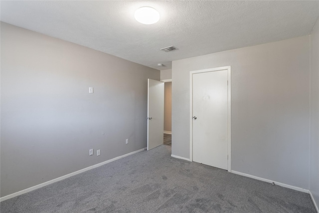 unfurnished room featuring carpet and a textured ceiling