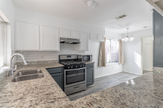 kitchen featuring backsplash, stainless steel appliances, sink, white cabinets, and a chandelier