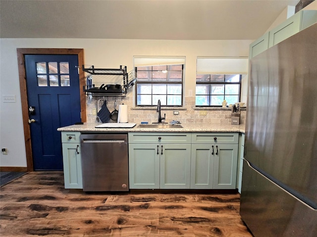 kitchen with appliances with stainless steel finishes, tasteful backsplash, green cabinets, and sink