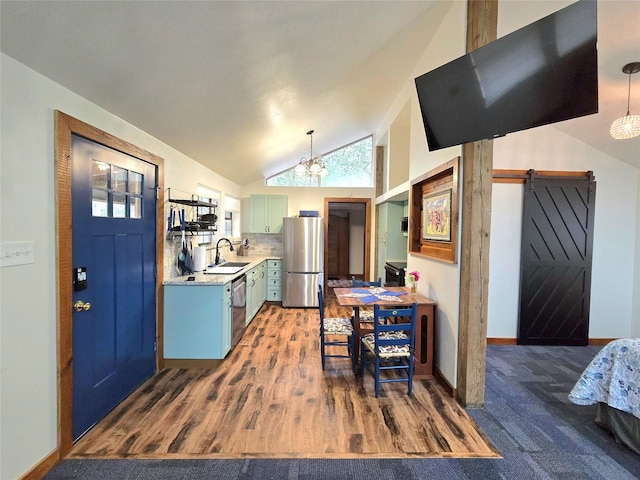 kitchen with sink, stainless steel appliances, tasteful backsplash, a barn door, and pendant lighting