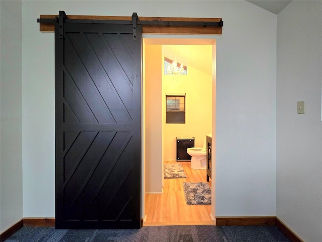 corridor with a barn door, carpet, and lofted ceiling