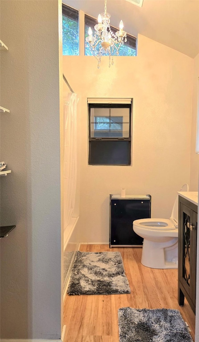 full bathroom with hardwood / wood-style floors, lofted ceiling, toilet, shower / tub combo with curtain, and a chandelier