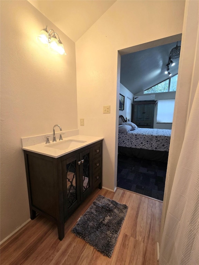 bathroom with vanity, hardwood / wood-style flooring, and lofted ceiling