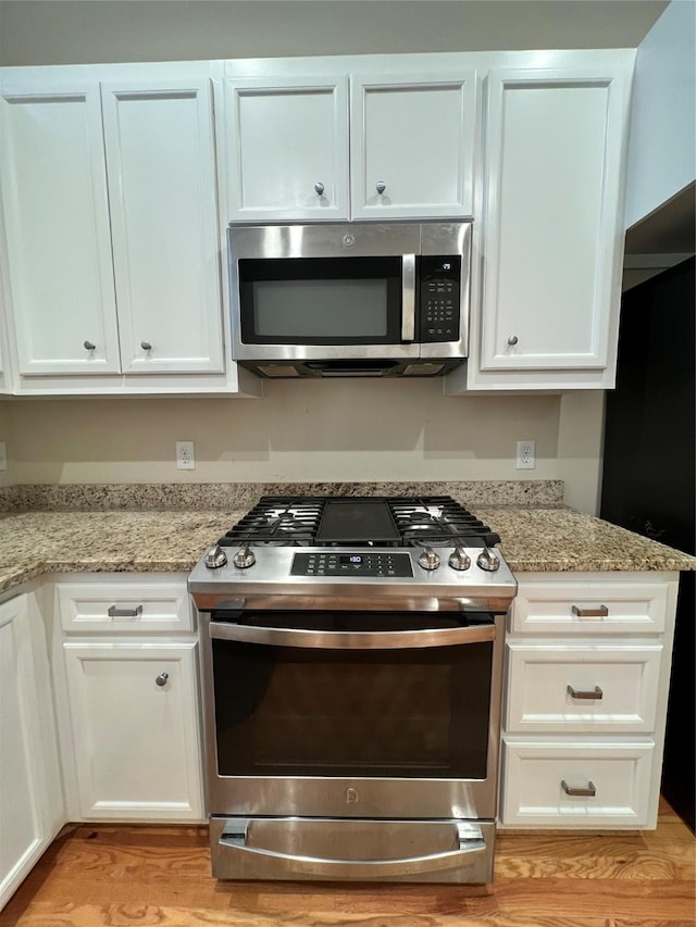 kitchen featuring light stone counters, white cabinets, and stainless steel appliances