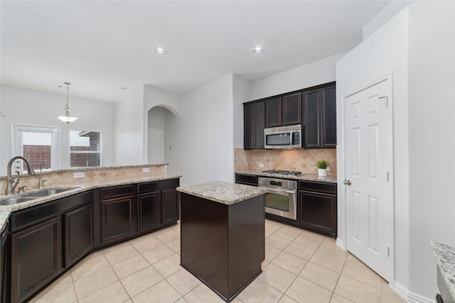 kitchen featuring sink, stainless steel appliances, light stone countertops, decorative backsplash, and decorative light fixtures