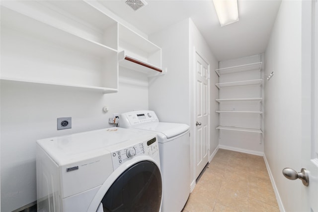 laundry area with washer and dryer and light tile patterned floors