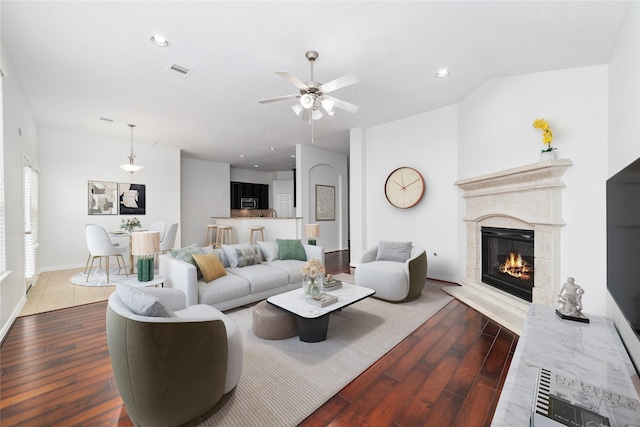 living room with wood-type flooring, ceiling fan, and a high end fireplace