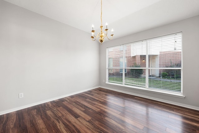 spare room with dark hardwood / wood-style floors and a chandelier