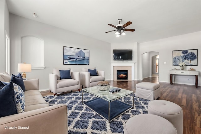 living room with ceiling fan, dark hardwood / wood-style flooring, and a tiled fireplace