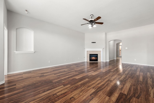 unfurnished living room with a tile fireplace, ceiling fan, and dark hardwood / wood-style floors