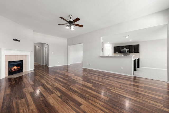 unfurnished living room with a textured ceiling, dark hardwood / wood-style floors, ceiling fan, and a fireplace