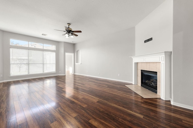 unfurnished living room featuring ceiling fan, wood-type flooring, and a tiled fireplace