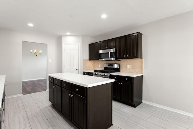 kitchen featuring hanging light fixtures, stainless steel appliances, a notable chandelier, decorative backsplash, and a kitchen island