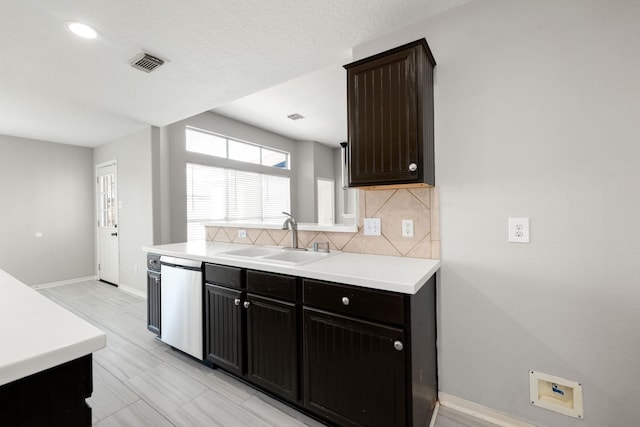 kitchen featuring decorative backsplash, stainless steel dishwasher, dark brown cabinets, a textured ceiling, and sink