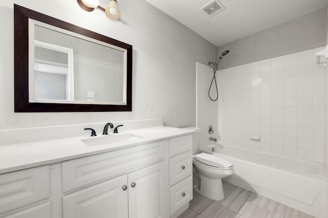 full bathroom featuring vanity, tiled shower / bath combo, and toilet