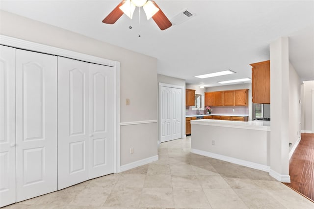 kitchen featuring backsplash, kitchen peninsula, and ceiling fan