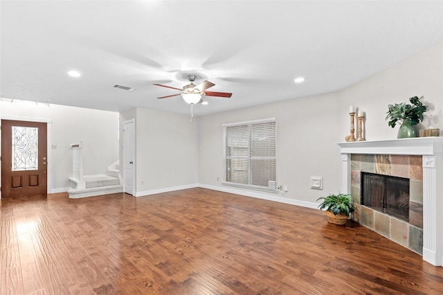 unfurnished living room featuring hardwood / wood-style flooring, ceiling fan, and a tiled fireplace