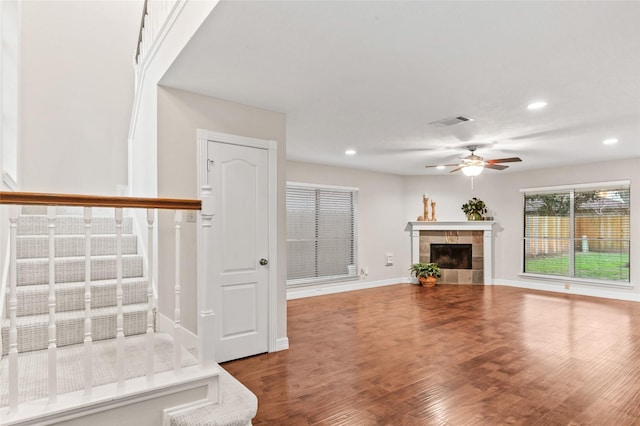 unfurnished living room featuring baseboards, visible vents, a ceiling fan, wood finished floors, and a fireplace