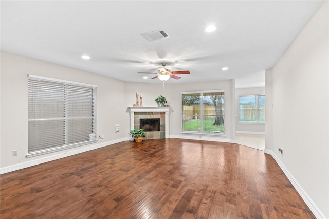 unfurnished living room featuring a tiled fireplace, ceiling fan, and hardwood / wood-style flooring