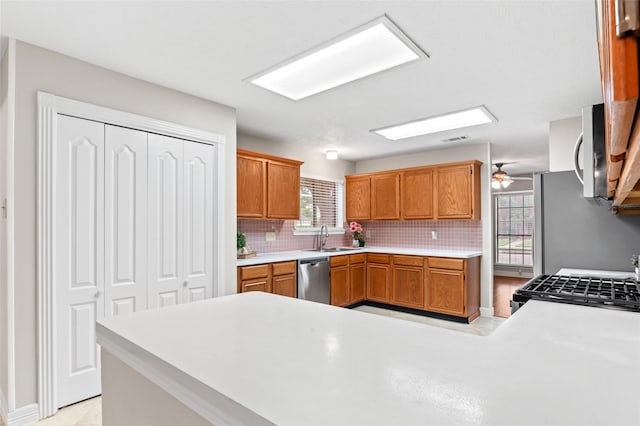 kitchen featuring backsplash, range, sink, stainless steel dishwasher, and kitchen peninsula