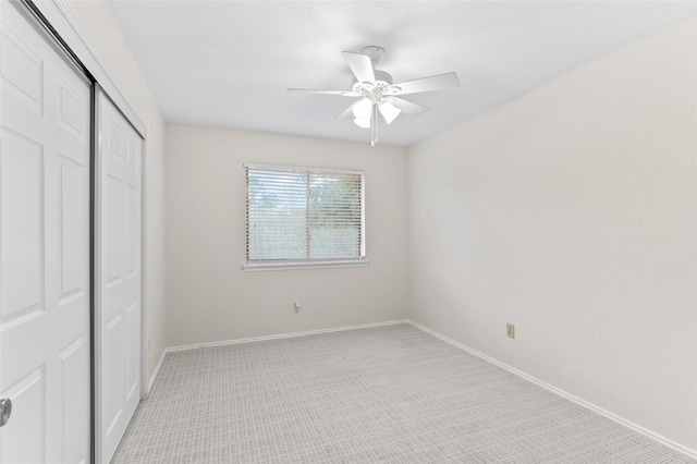 unfurnished bedroom featuring ceiling fan, light carpet, and a closet