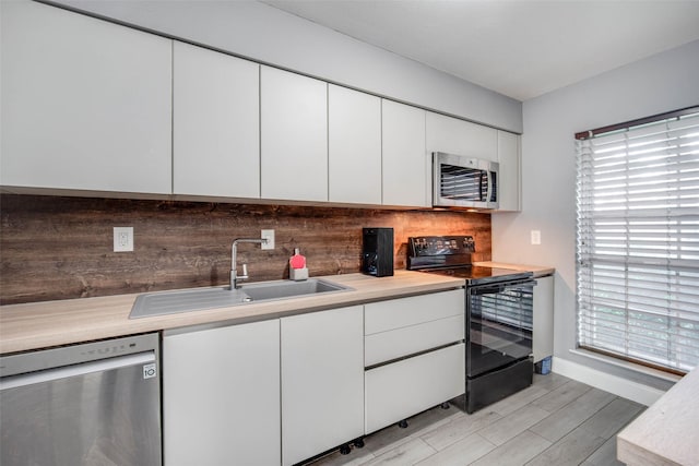 kitchen with white cabinetry, sink, light hardwood / wood-style flooring, decorative backsplash, and appliances with stainless steel finishes