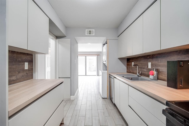 kitchen featuring dishwasher, sink, light wood-type flooring, tasteful backsplash, and white cabinetry