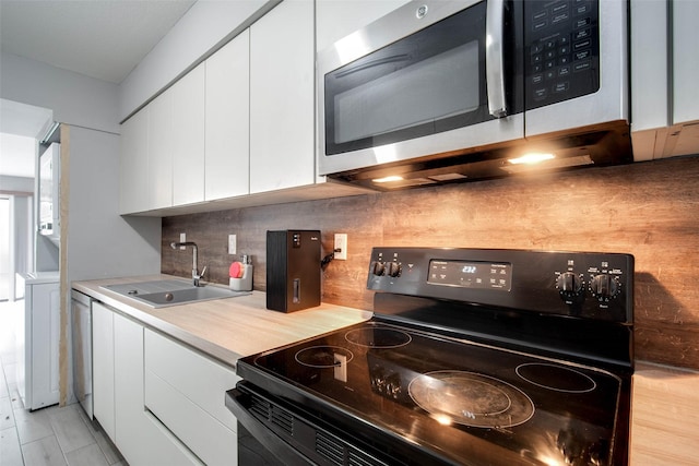 kitchen with appliances with stainless steel finishes, tasteful backsplash, white cabinetry, and sink