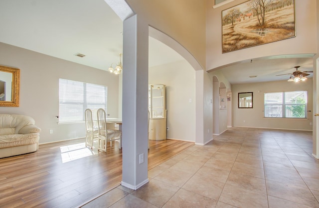 tiled entrance foyer with ceiling fan with notable chandelier